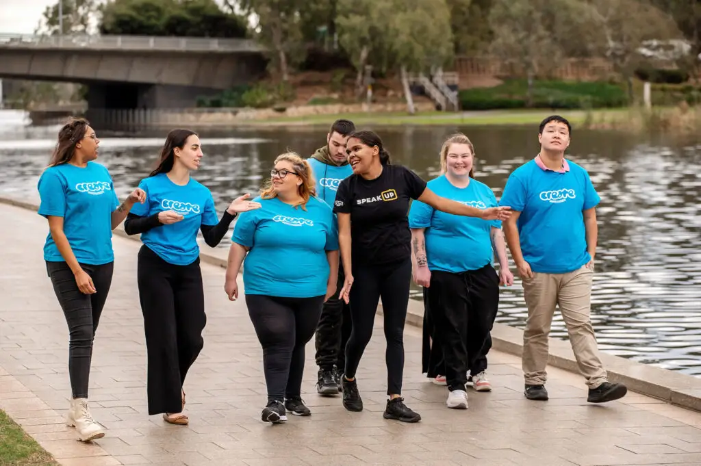 A group of young people in CREATE shirts walking along the river